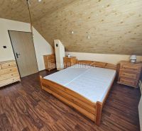 A bedroom in a family house with a wood-patterned floor and wooden furniture.