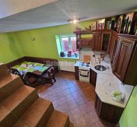 A kitchen in a family house with a staircase, wooden furniture, and green walls.