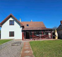 A family house in Malá Lehota with a veranda and a garden under the blue sky.