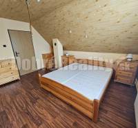 An attic bedroom in a family house with wooden furniture and a sloped ceiling.