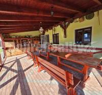 Covered terrace with wooden seating and cabinets in a family house.