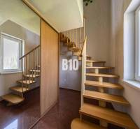 A staircase in a family house with wooden steps, a large window, and a mirrored wall.
