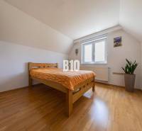 A bedroom in a family house with a sloped ceiling and a wooden bed.