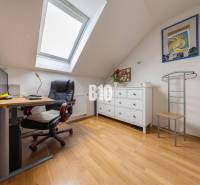 A study in a family house with a desk, an armchair, and a chest of drawers under a skylight.