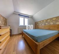 Bedroom with wooden furniture in a family house, floral wallpaper, wooden floor.