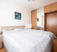 Bedroom in a 3-room apartment with a double bed, built-in wardrobe, and a painting on the wall.