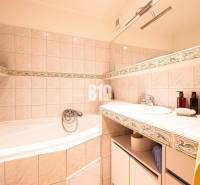 A bathroom with a bathtub and a sink in a 3-room apartment, decorated with ceramic tiles.