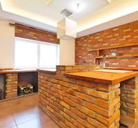 A kitchen in a family house with brick walls and a wooden counter.