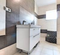 A bathroom in a family house with light tiles and a double sink.