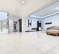 Living room with a sofa and staircase in a family house, light tiles, light walls.