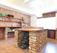 A kitchen in a family house with brick details and wooden shelves.