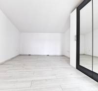 A spacious, white room with a mirror and a floor in a family house.