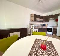 A kitchen with a stove and a dining table in a 3-room apartment.