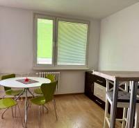 Dining area with a table and green chairs in a 3-room apartment.