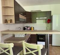 A kitchen in a 3-room apartment with light cabinets, a bar counter, and appliances.