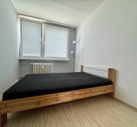 A simply furnished bedroom with a bed and a lamp in a 3-room apartment.