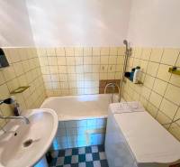 Bathroom with a bathtub, sink, and washing machine in a 2-room apartment.