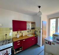 The kitchen of a two-room apartment with red cabinets and an older gas stove.
