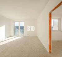 An empty interior of a family house with large plastic windows and a concrete floor.