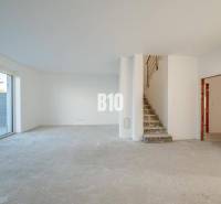 A spacious interior with an unfinished floor and a staircase in a family house.