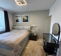 Bedroom in a family house with a bed, lamp, table, and wall decoration.