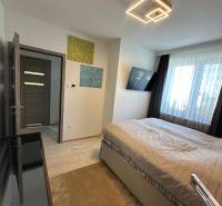 Bedroom in a family house with light, television, paintings, and a large window.