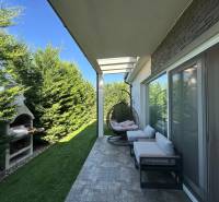 The terrace of a family house in Gabčíkovo with comfortable seating, a swing, and a fireplace.