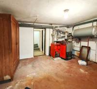 Boiler room in a family house containing a boiler, reservoir, and an old cabinet.