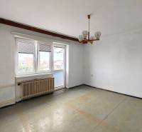 Room in a family house with white walls, a window, a radiator, and a chandelier.