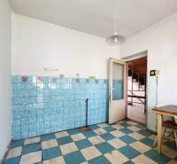 A kitchen in a family house with older tiles and wooden furniture.
