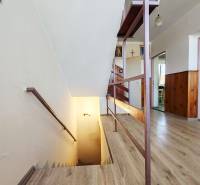A hallway with a wooden staircase and moldings in a family house.