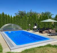 A swimming pool with a roof, garden furniture, and a sunshade at a family house in Trenčianske Jastrabie.