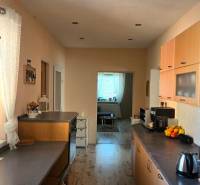 A kitchen in a family house with wooden cabinets, appliances, and a window with a view.
