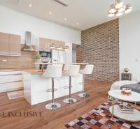 A kitchen with an island and bar stools in a family house, brick wall.