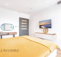 Bright bedroom in a family house with a TV, mirror, and yellow blanket on the bed.