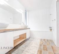 A bathroom in a family house with sinks, white walls, and wooden flooring.