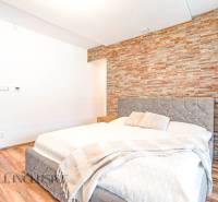 A bedroom in a family house with a stone wall, an elegant bed, and decorative accessories.