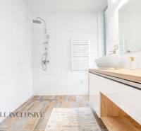 A bathroom in a family house with a sink, shower, and white tiles.