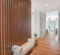 A hallway of a family house with a wooden wall, a light bench, and decorative elements.