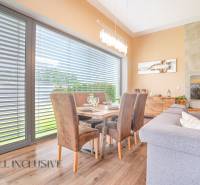 Dining area in a family house with a wooden table, chairs, and a shaded window.
