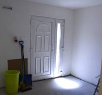 An empty room with white doors, a bucket, and cleaning supplies in commercial premises.