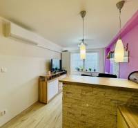 A kitchen in a 2-room apartment with a bar counter, a television, and decorative lamps.