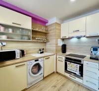 A kitchen in a 2-room apartment with white cabinets, wooden decor, and appliances.