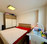 Bedroom in a two-room apartment with a double bed, wardrobe, and baby crib.