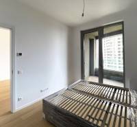 A bright room with a bed next to large balcony doors, 2-room apartment.