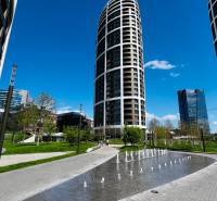 Modern high-rise buildings with a fountain and park greenery on Továrenská Street in Bratislava.