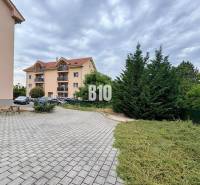 An apartment building in Nitra with three floors surrounded by greenery and a parking lot.