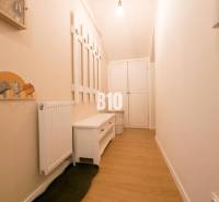 A narrow hallway in a 3-room apartment with a coat rack, a bench, and cabinets on a light floor.