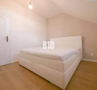 A bedroom in a 3-room apartment with a white bed and wooden flooring.