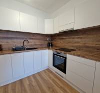 White kitchen in a 2-room apartment with a wooden countertop and floor.